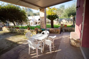 Eine Terrasse im Freien mit Tisch und Stühlen, umgeben von Steinmauern und Blumentöpfen.