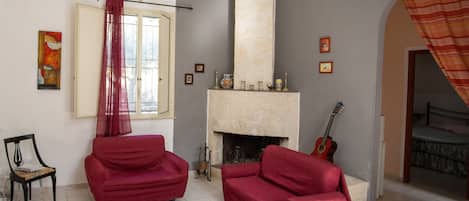 Una sala de estar con dos sofás rojos, un tapete a cuadros, una chimenea y una guitarra.