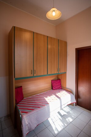 Ein Zimmer mit einem Bett, einem Kleiderschrank und einer Tür.