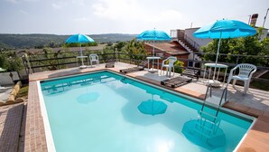 A rectangular pool with a clear blue water surface, surrounded by a tiled deck area with lounge chairs and umbrellas. - Villa 'La Panchina' with private pool, Wi-Fi, and air conditioning (Noto)
