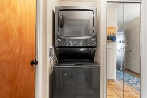 A compact kitchen with a built-in oven and microwave, a small countertop, and a door leading to another room. - 🏖️Top-Floor Kona Condo with A/C & Private Lanai (Kailua Kona)