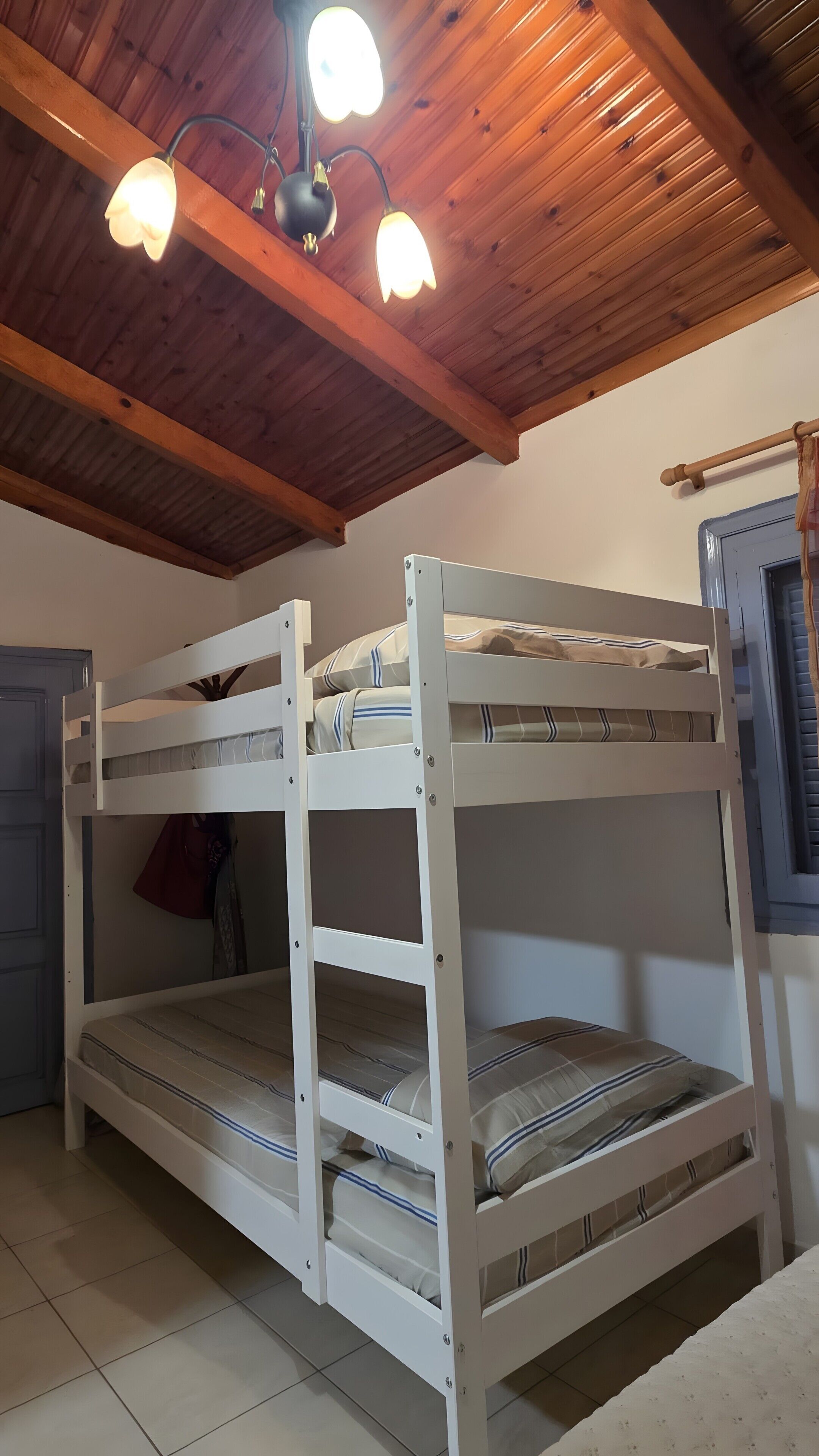 A bunk bed with a wooden ceiling and a hanging light fixture.