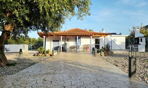 A building with a tiled roof, a covered patio area, and a paved walkway leading to the entrance.