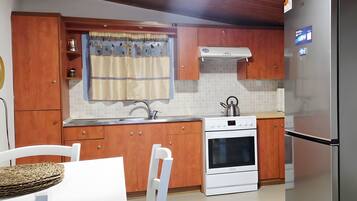 Una cocina con armarios de madera, una estufa blanca y un refrigerador de acero inoxidable.