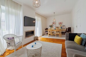 Ein modernes Wohnzimmer mit Flachbildfernseher, Kamin, Essbereich mit Tisch und Stühlen sowie einer Couch.