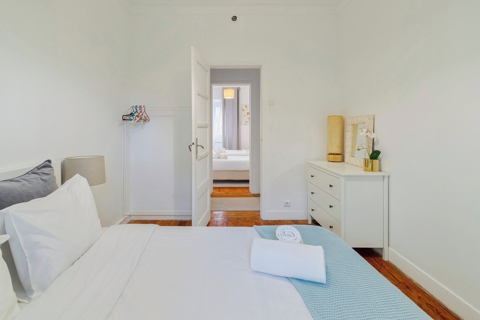 Une chambre d’hôtel comprenant un lit, une commode, un miroir et une porte donnant sur une autre pièce.