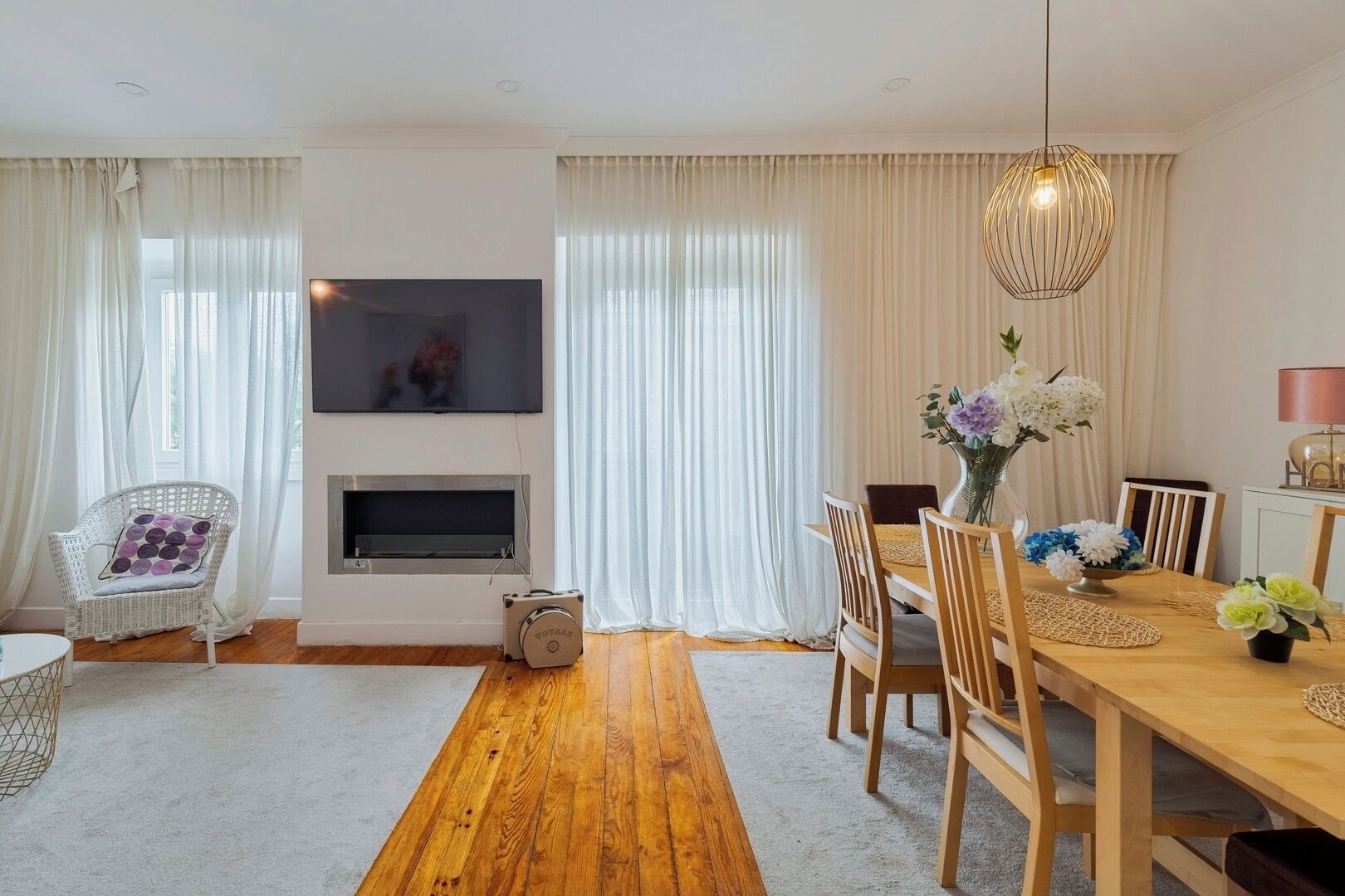 A living room with a television, a fireplace, a dining table with chairs, and a sofa.