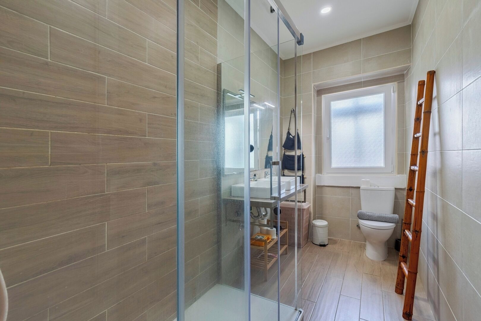 Un baño moderno con cabina de ducha de vidrio, inodoro y ventana.