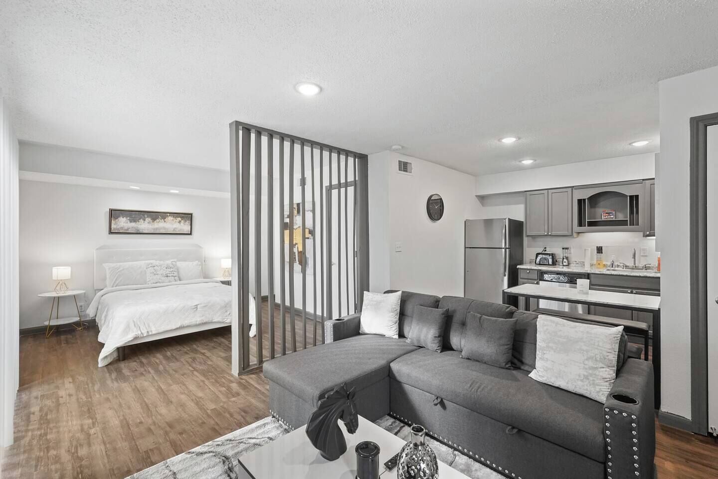 A modern apartment with a bedroom, living area, and kitchenette.