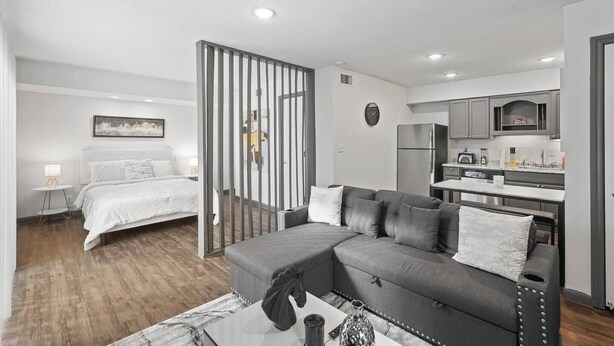 Un apartamento moderno con un dormitorio, sala de estar y kitchenette.