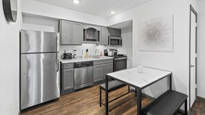 Una cocina moderna con electrodomésticos de acero inoxidable, encimera de mármol y un comedor con banco.