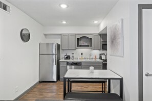 A compact kitchen with a refrigerator, stove, sink, and a clock on the wall. - Modern King Studio, Pool, Near MD Anderson and NRG (Houston)