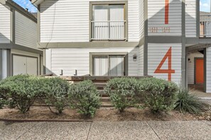 Un bâtiment à deux étages, avec le chiffre « 4 » peint sur le côté, un garage et un petit jardin agrémenté d’arbustes.