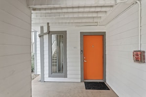 Un bâtiment blanc avec une porte grise et une porte orange vif.