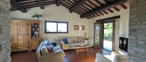 Amplia sala de estar con techos altos, chimenea, ventana grande y pared de piedra.