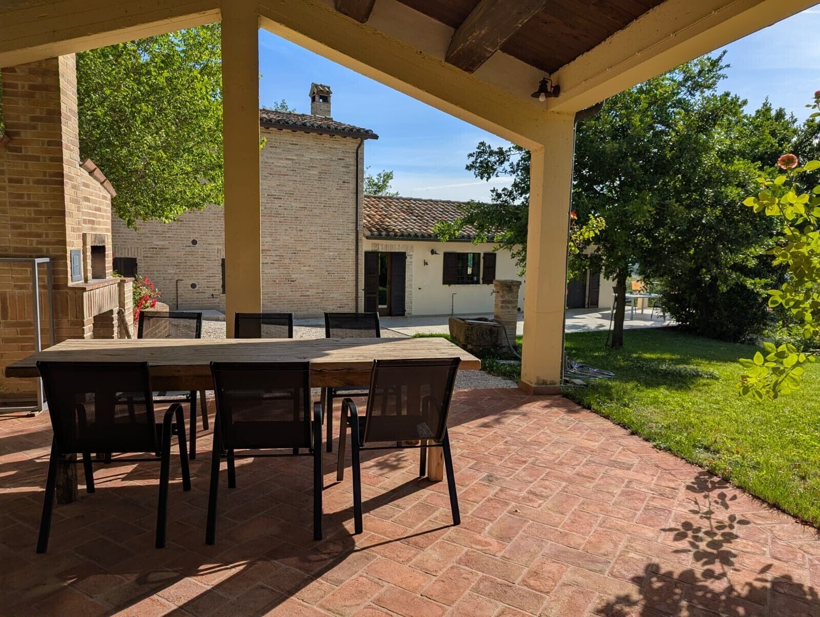 An outdoor patio with a brick table and chairs, surrounded by a brick wall and greenery.