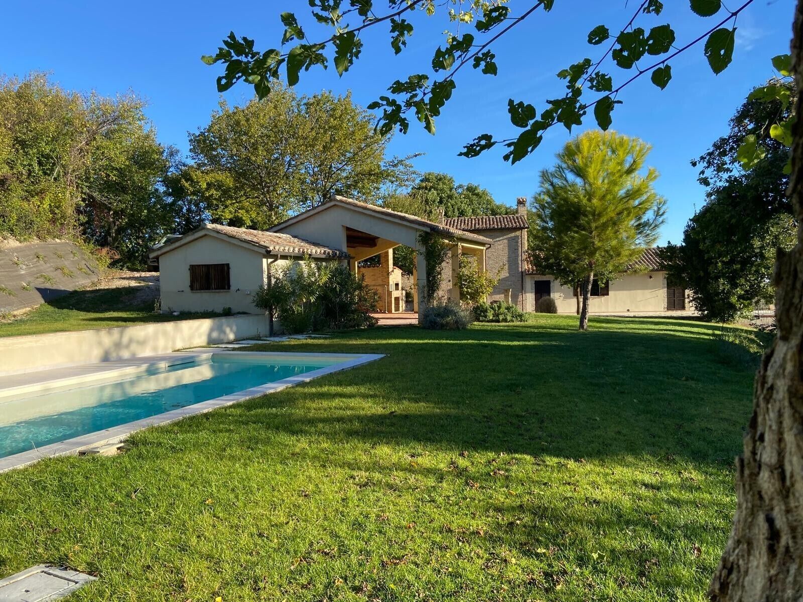 Ein Wohnhaus mit Swimmingpool, einer überdachten Terrasse und einem gepflegten Rasen.