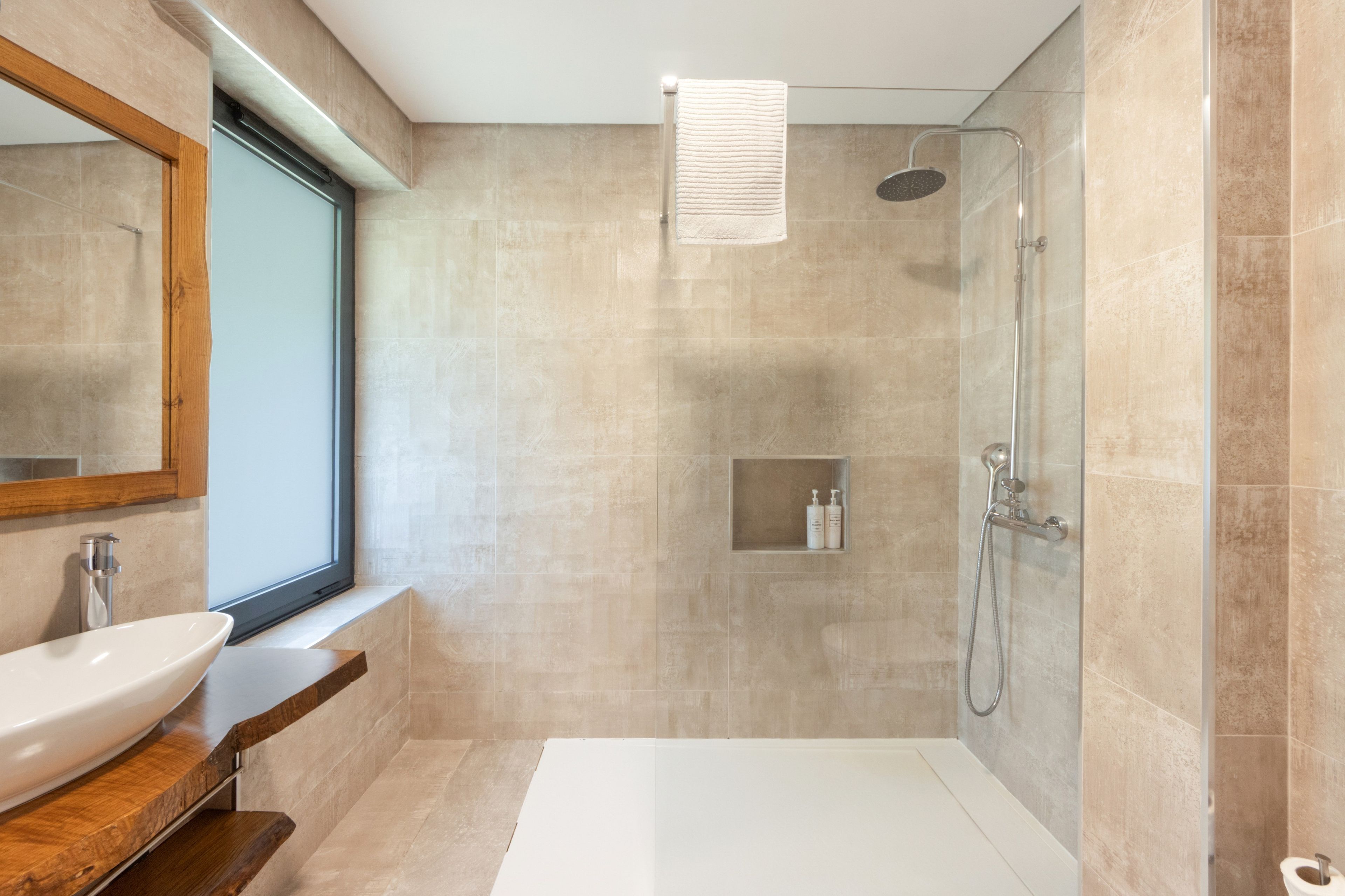 Een moderne badkamer met een bad, een douche en een wastafel met spiegel.