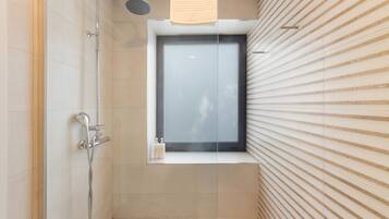 A modern bathroom with a shower, a window, and a towel hanging on the wall.
