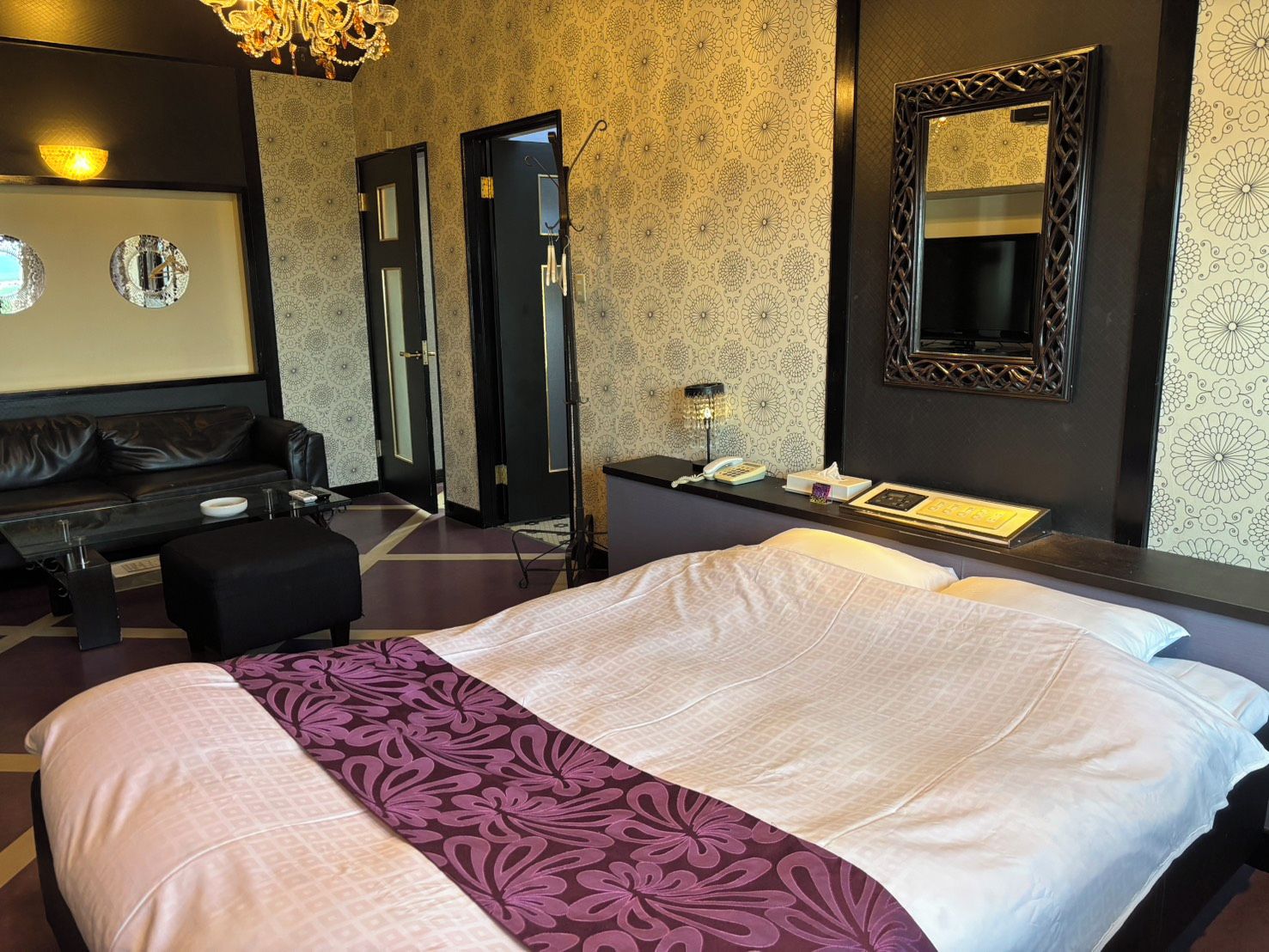 Una habitación de hotel con una cama grande, una zona de estar con sofá, un escritorio y un espejo.