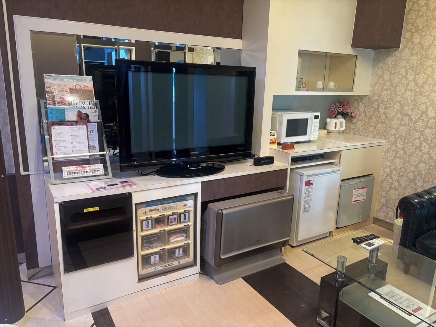 Una kitchenette compacta con una televisión de pantalla plana, un microondas y un refrigerador pequeño.