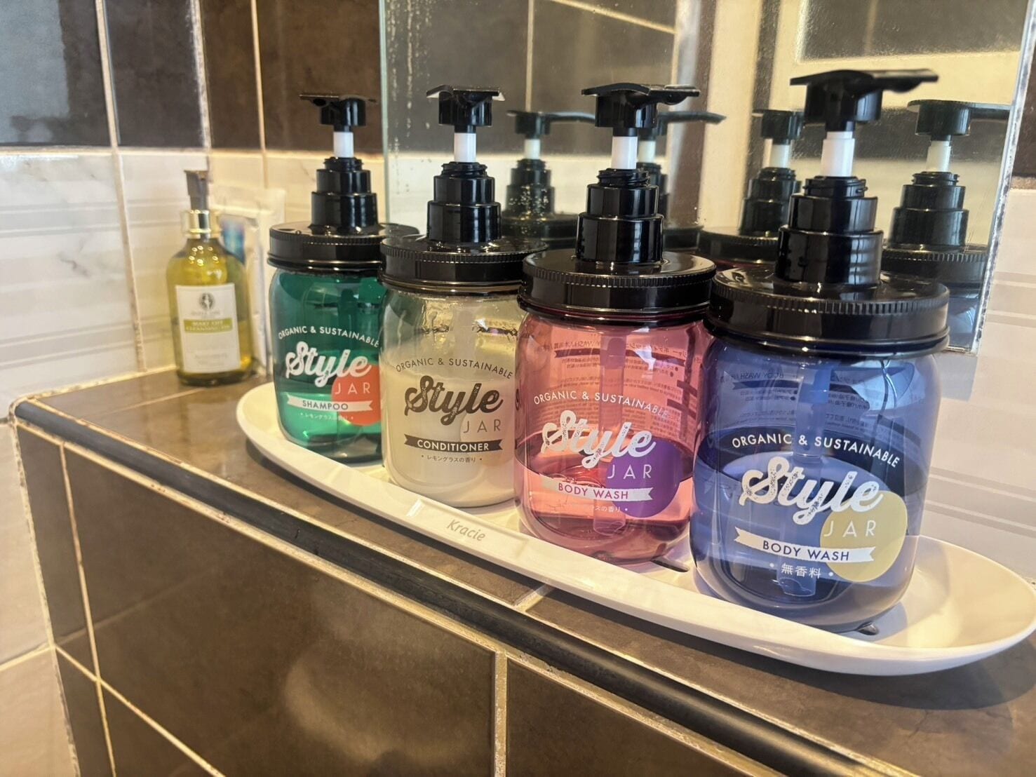 A bathroom shelf with various Style Jar products including shampoo, conditioner, and body wash.
