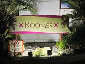 Señal para el RooMer del Hotel Ocean View, con un jardín tropical de fondo.
