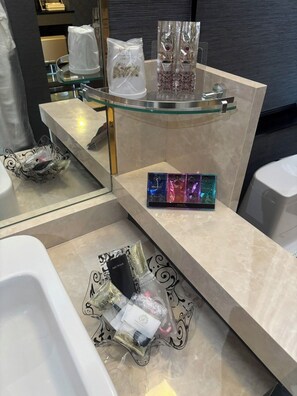 A bathroom with a glass shelf holding toiletries, a mirror, and a decorative item. - hotel roomer (Hitachi)