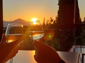 Due mani che sorreggono bicchieri d'acqua con un tramonto sullo sfondo.