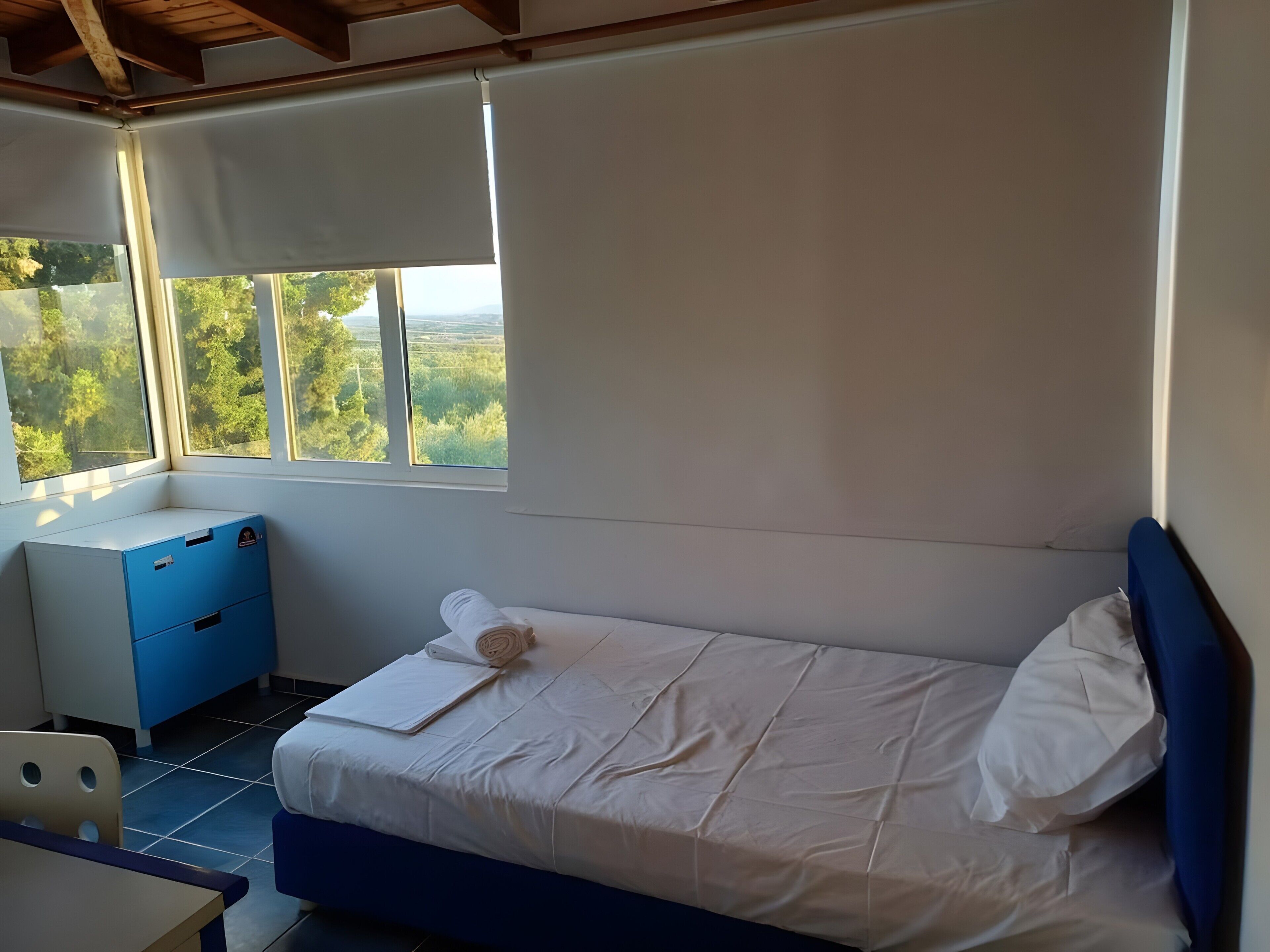 Una camera da letto con un letto, una scrivania e una finestra vista verde.