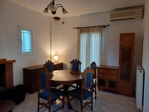 Zona pranzo con tavolo rotondo, quattro sedie, una lampada, una finestra e un armadietto.
