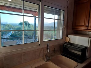 A kitchen with a large window, a sink, and a dish rack.
