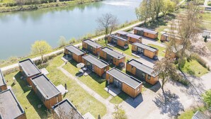 Ein Ufergrundstück mit modernen Blockhäusern, einem Fluss und einer hügeligen Landschaft im Hintergrund.
