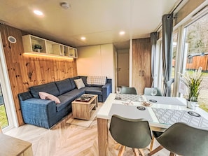 A modern living room with a sofa, coffee table, and dining table set. - Tiny Haus Christas Oase by Interhome (Riedenburg)