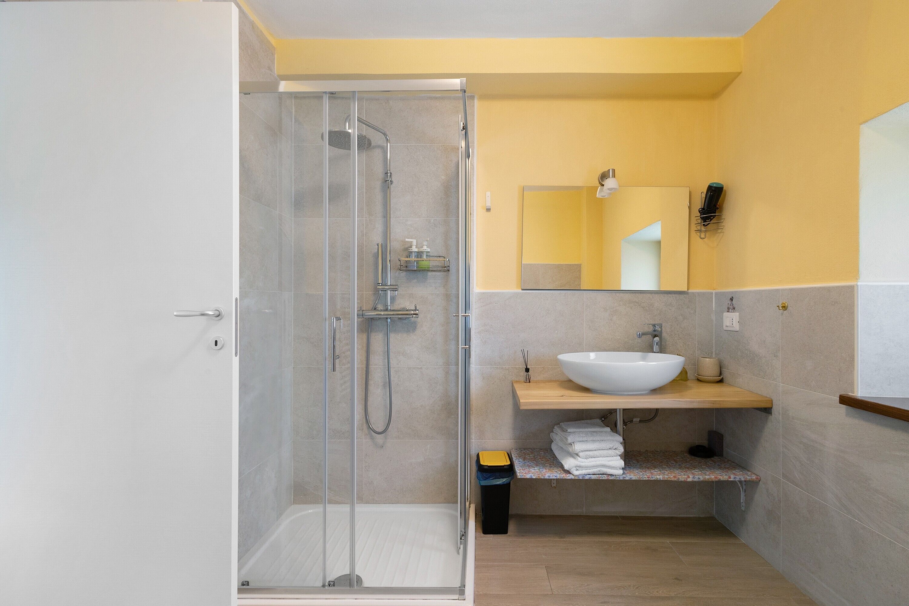 Un baño moderno con cabina de ducha de vidrio, un lavabo blanco y un espejo sobre el lavabo.