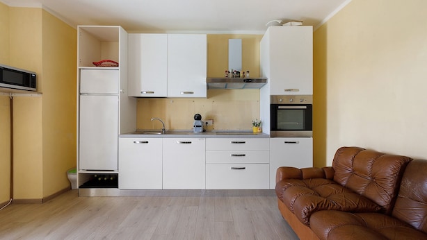 A compact kitchen with white cabinets, a microwave, a coffee maker, and a stove.