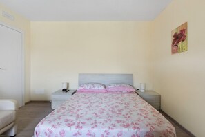 Une chambre à coucher avec un lit, des tables de chevet, une chaise et un tableau au mur.