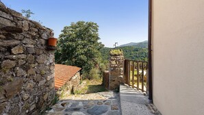 A stone pathway leading to a rustic building with a tiled roof and a wooden gate.