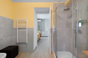 Een moderne badkamer met een douche, toilet en handdoekhouder.