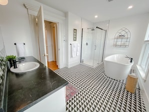Ein Badezimmer mit schwarzem Waschtisch, einer freistehenden Badewanne und einem strukturierten Boden.