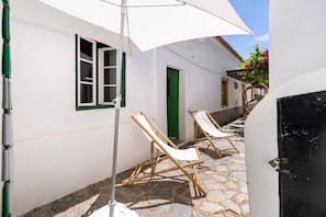 A courtyard with white walls, a green door, and two wooden lounge chairs under a white umbrella. - Villa 'Casa Do Rio' with Private Garden, Wi-Fi and Air Conditioning (Mértola)