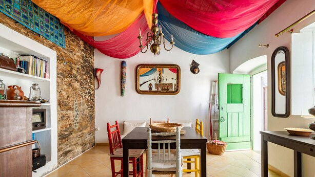 Un coin repas avec une table, des chaises et une porte verte en arrière-plan.