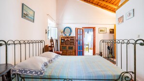 Une chambre à coucher comprenant un lit, une armoire en bois, un miroir et une porte donnant sur une autre pièce.