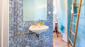 Une salle de bain avec un lavabo blanc, des carreaux de mosaïque bleus, un miroir et un rideau de douche.