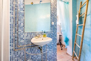 A bathroom with a white sink, blue mosaic tiles, a mirror, and a shower curtain.