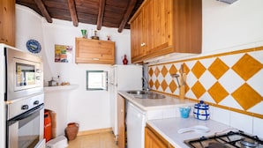 Une cuisine compacte avec des meubles en bois, une cuisinière à gaz, un four encastré et un évier.
