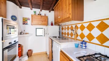Una cocina compacta con muebles de madera, una estufa a gas, horno integrado y un lavamanos.