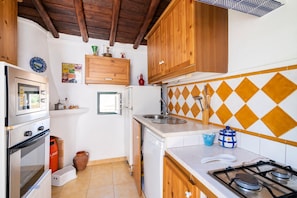 A compact kitchen with wooden cabinets, a gas stove, a built-in oven, and a sink.