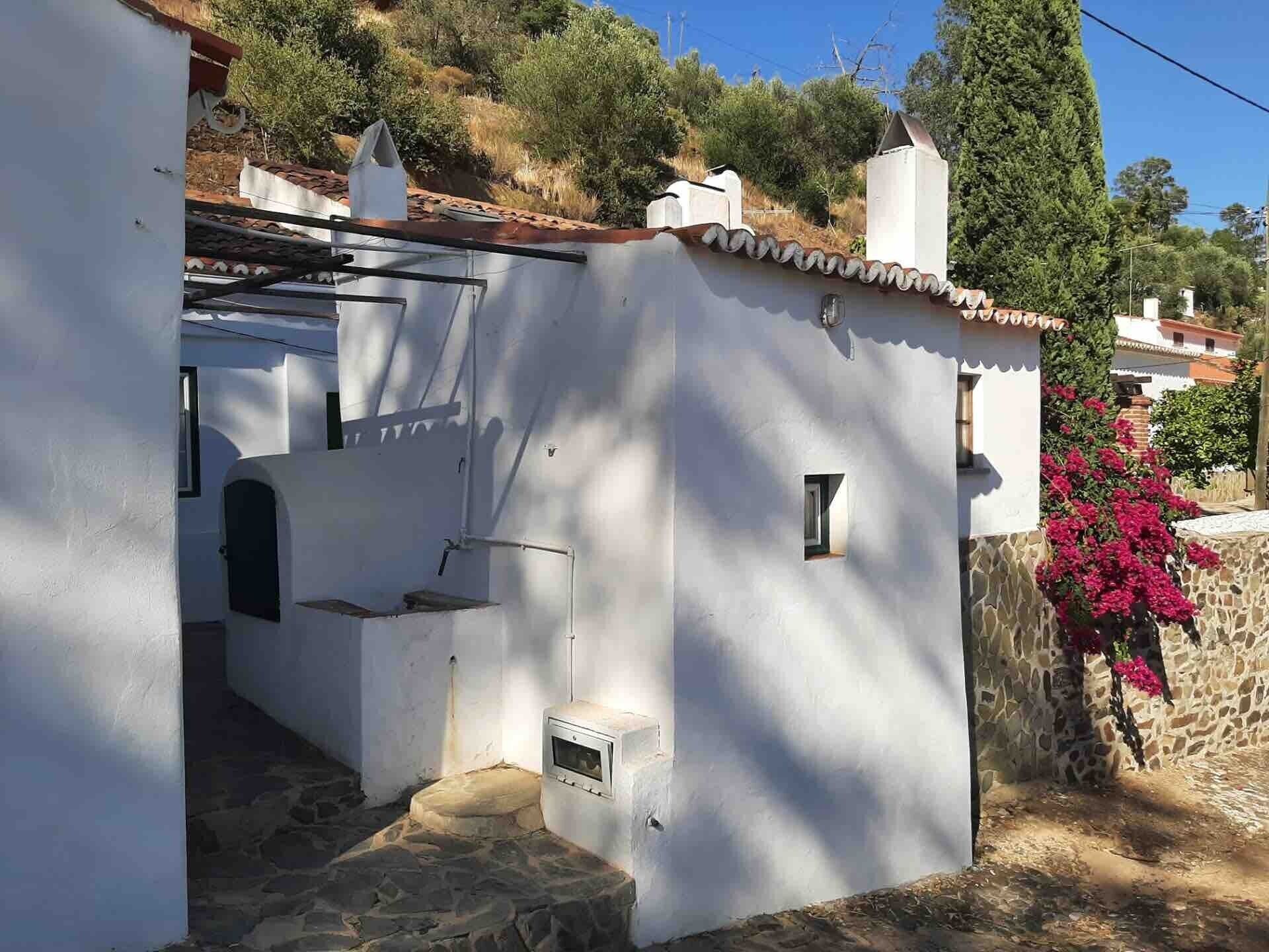 Un bâtiment blanc avec des fondations en pierre, une petite fenêtre et une porte.