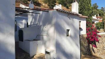 Un bâtiment blanc avec des fondations en pierre, une petite fenêtre et une porte.